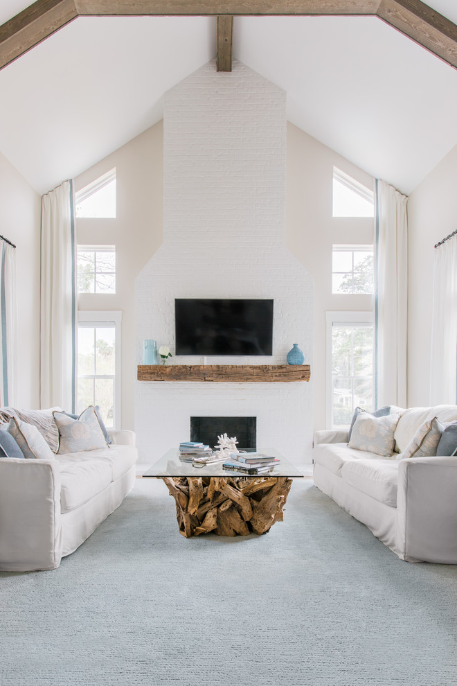 Inspiration for a large beach style open concept living room in Jacksonville with a standard fireplace, a brick fireplace surround, grey walls, carpet, a wall-mounted tv and blue floor.