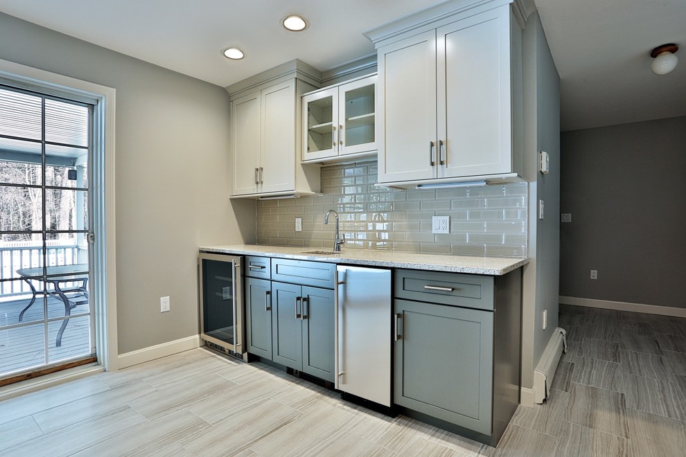 Inspiration for a mid-sized transitional single-wall wet bar in Boston with an undermount sink, shaker cabinets, white cabinets, granite benchtops, grey splashback, subway tile splashback, porcelain floors and beige floor.