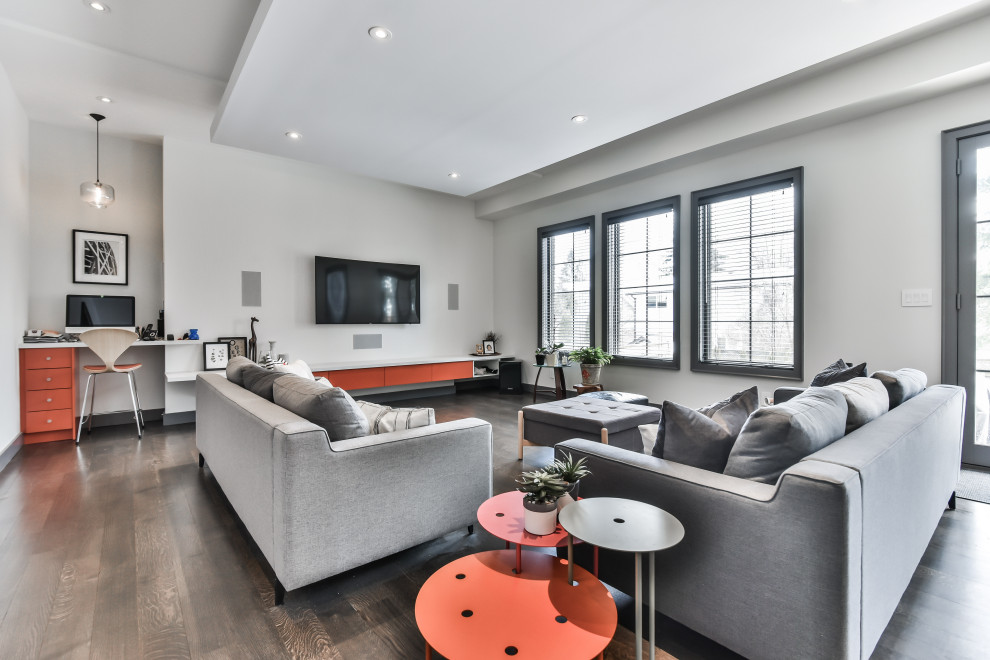 Photo of a contemporary open concept living room in Toronto with white walls, medium hardwood floors, no fireplace, a wall-mounted tv and brown floor.