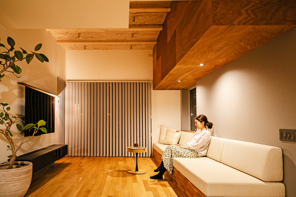 Offenes Modernes Wohnzimmer ohne Kamin mit grauer Wandfarbe, hellem Holzboden und freigelegten Dachbalken in Sonstige