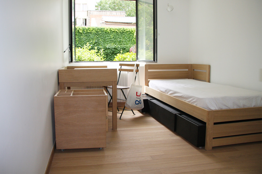 This is an example of a small contemporary master bedroom in Paris with white walls and light hardwood floors.
