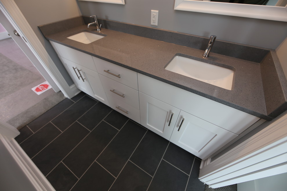 Mid-sized arts and crafts kids bathroom in Chicago with flat-panel cabinets, white cabinets, an alcove tub, a shower/bathtub combo, a two-piece toilet, gray tile, porcelain tile, grey walls, porcelain floors, an undermount sink, quartzite benchtops, black floor and a shower curtain.