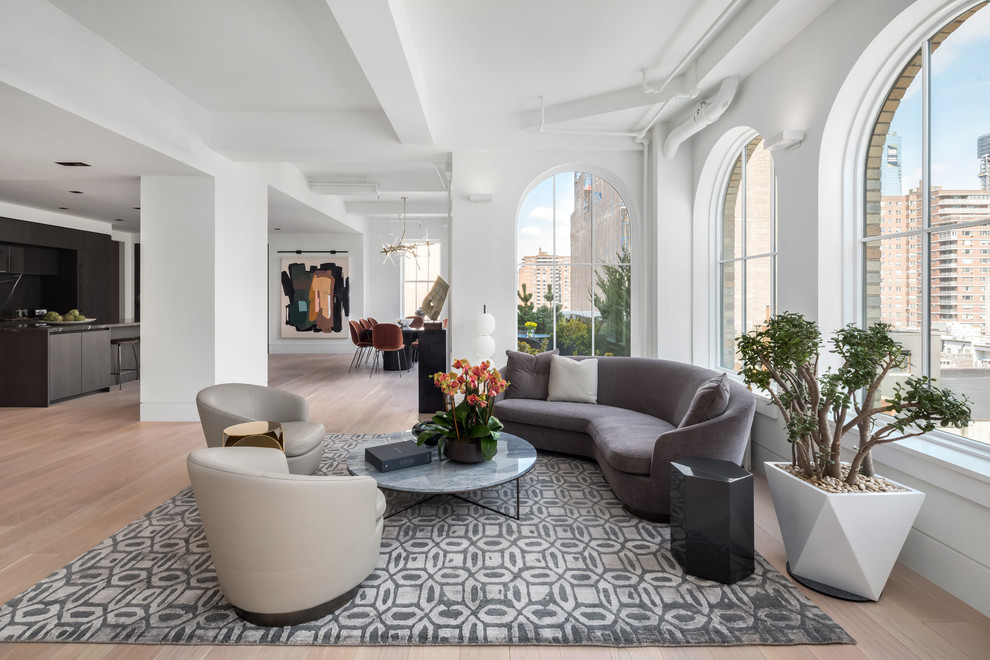 This is an example of a large contemporary formal open concept living room in New York with white walls, light hardwood floors, no fireplace and no tv.