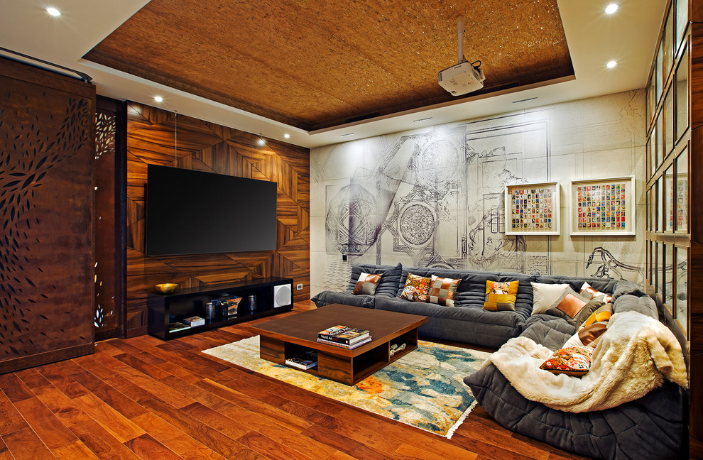 Photo of a mid-sized contemporary enclosed family room in Bengaluru with medium hardwood floors, a wall-mounted tv and brown floor.