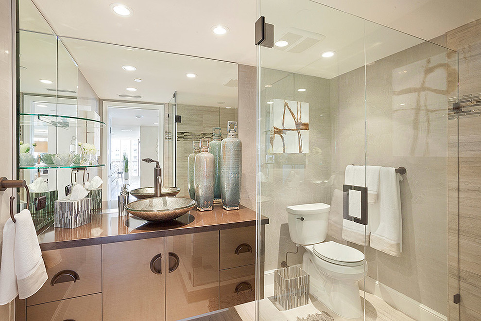 Inspiration for a mid-sized contemporary 3/4 bathroom in Miami with beige walls, brown cabinets, flat-panel cabinets, a corner shower, a two-piece toilet, multi-coloured tile, glass tile, a vessel sink, beige floor, a hinged shower door and brown benchtops.