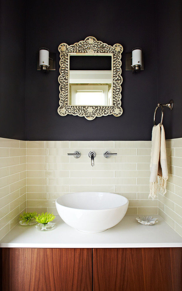 This is an example of a small contemporary powder room in San Francisco with a vessel sink, flat-panel cabinets, medium wood cabinets, engineered quartz benchtops, black walls, beige tile and white benchtops.