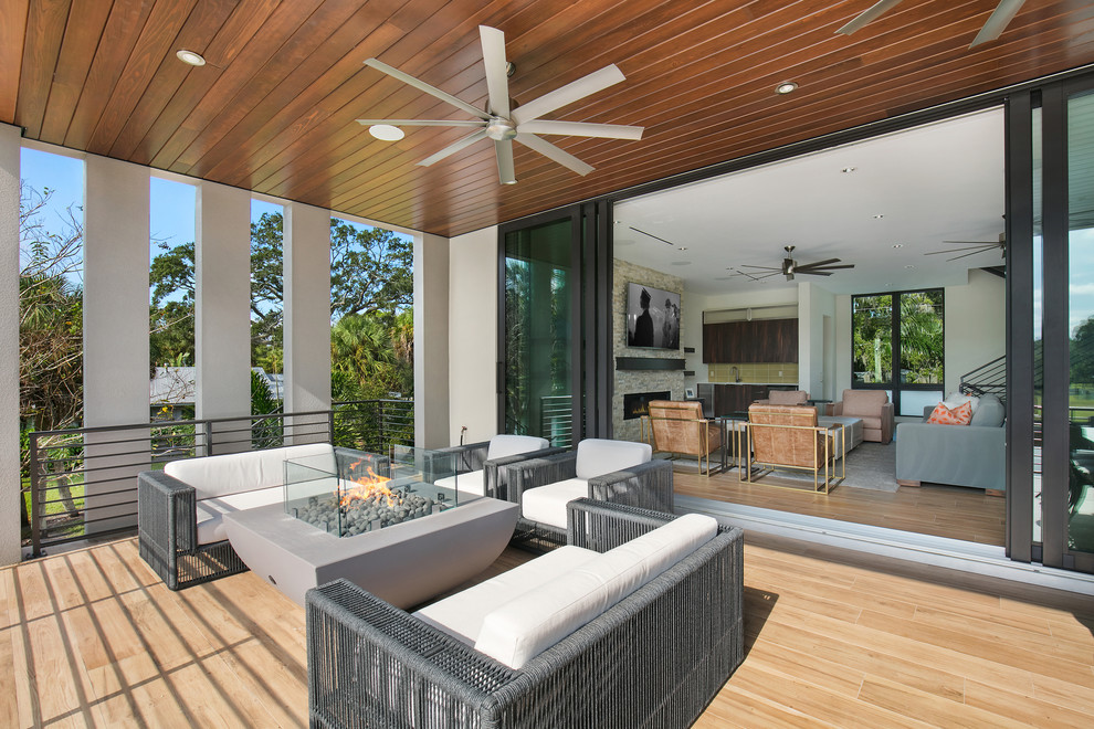 Mid-sized modern balcony in Tampa with a fire feature, a roof extension and metal railing.