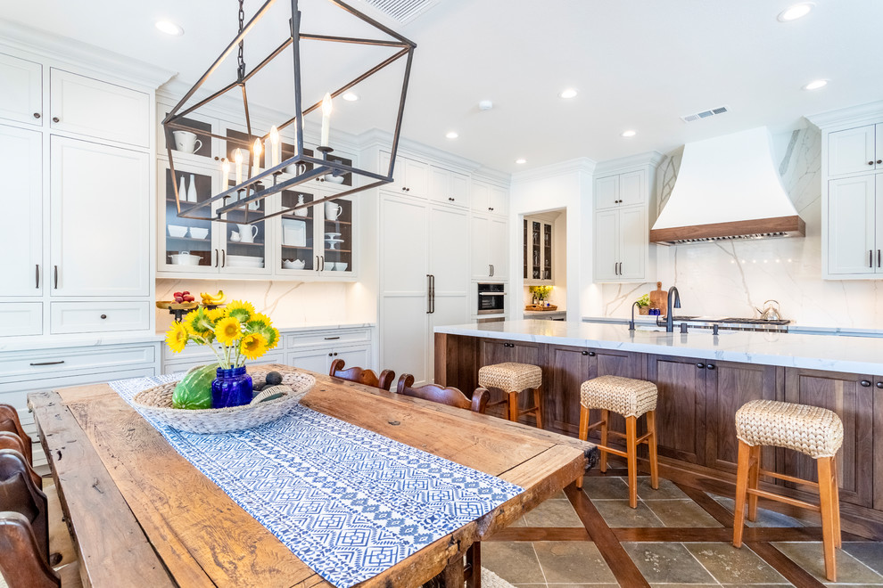 Inspiration for a large transitional single-wall eat-in kitchen in Los Angeles with shaker cabinets, white cabinets, quartzite benchtops, white splashback, stone slab splashback, with island, white benchtop, an undermount sink, stainless steel appliances and brown floor.