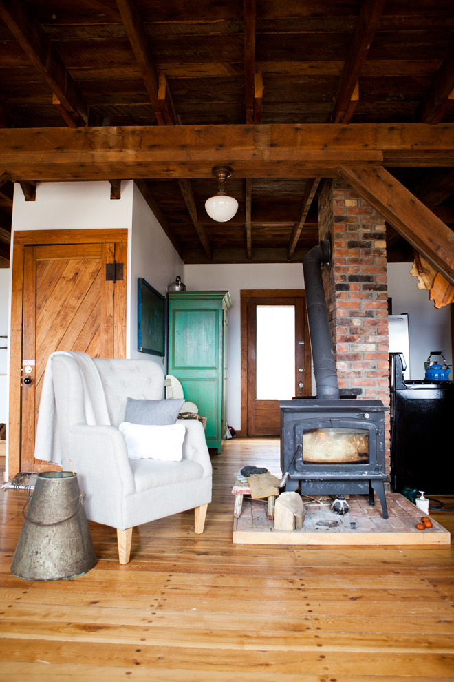 This is an example of a country living room in Burlington with medium hardwood floors and a wood stove.