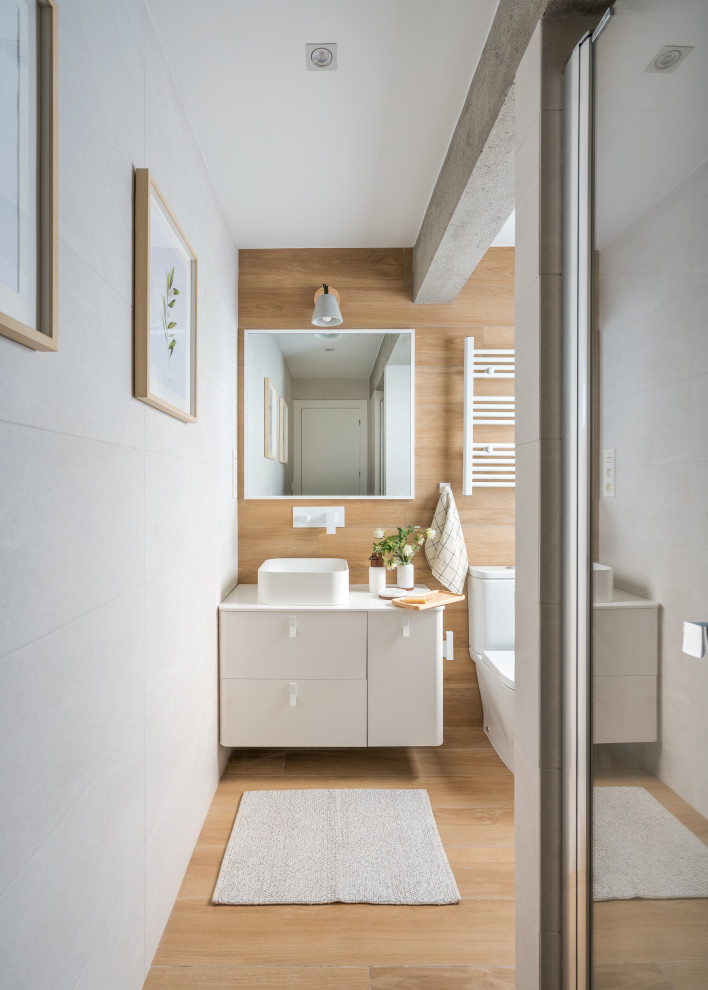 Photo of a small mediterranean master bathroom in Bilbao with flat-panel cabinets, an alcove shower, a one-piece toilet, white tile, ceramic tile, grey walls, medium hardwood floors, a vessel sink, onyx benchtops, brown floor, a hinged shower door, white benchtops, a single vanity and a floating vanity.