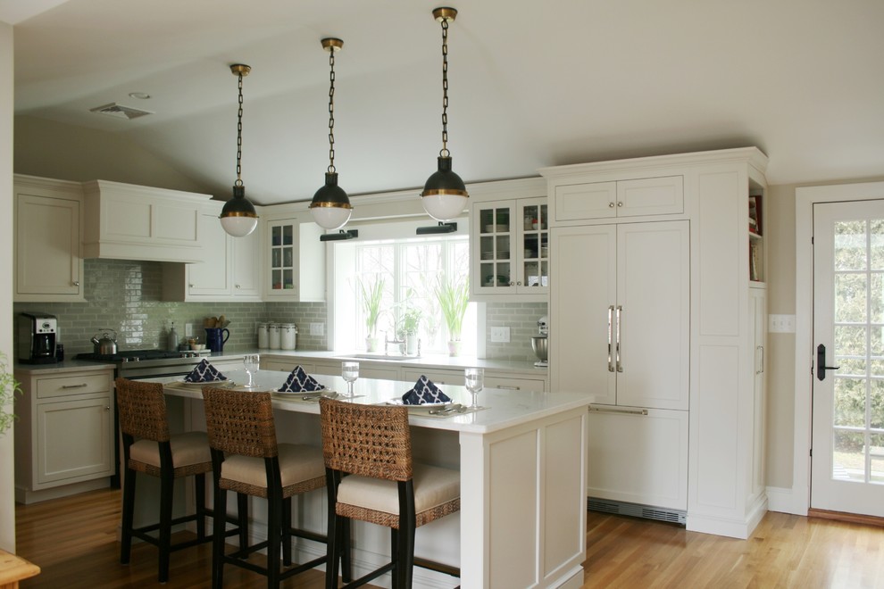 Inspiration for a mid-sized transitional l-shaped eat-in kitchen in Boston with an undermount sink, shaker cabinets, white cabinets, grey splashback, subway tile splashback, panelled appliances, medium hardwood floors and with island.