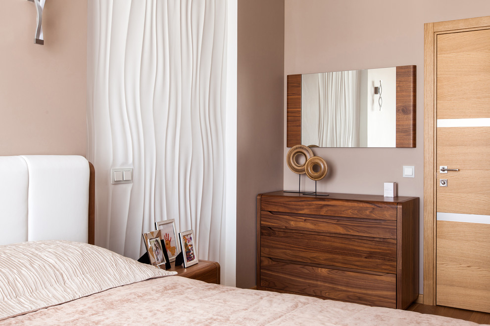 This is an example of a contemporary master bedroom in Moscow with beige walls and medium hardwood floors.