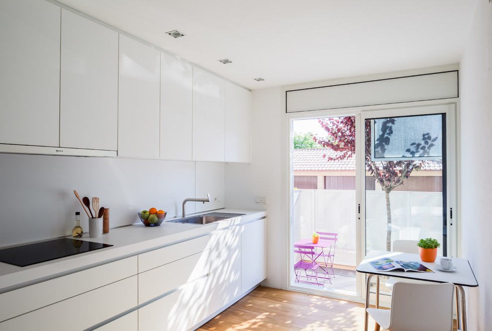 Photo of a contemporary l-shaped open plan kitchen in Other with a single-bowl sink, flat-panel cabinets, white cabinets, laminate benchtops, white splashback, stainless steel appliances, medium hardwood floors, no island and brown floor.