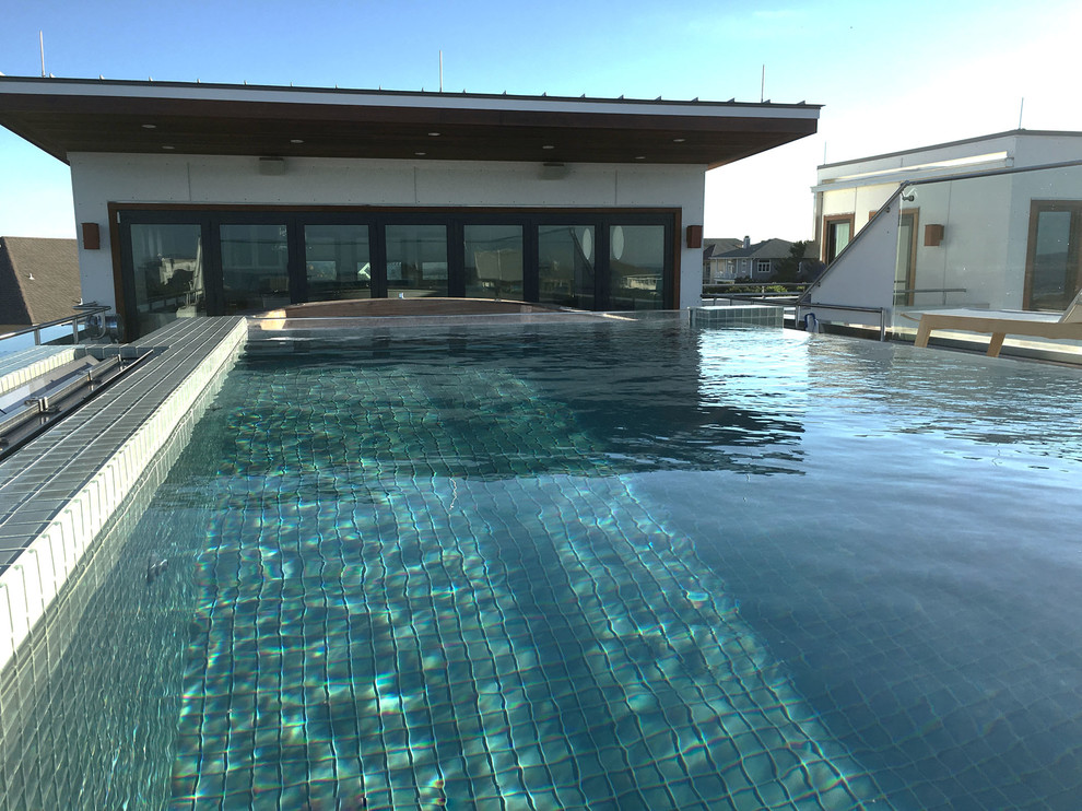 Design ideas for a contemporary rooftop rectangular infinity pool in Other with decking.