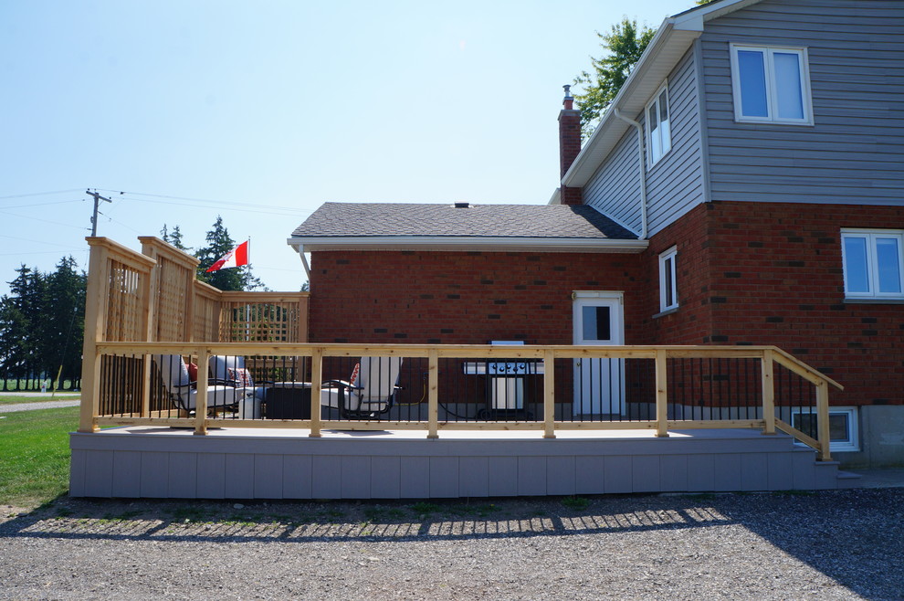 Example of a large transitional backyard deck design in Toronto with a fire pit and no cover