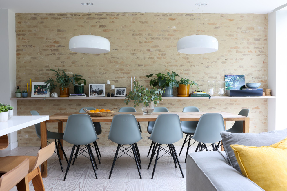 Inspiration pour une salle à manger design avec un mur beige, parquet clair, un sol beige et un mur en parement de brique.