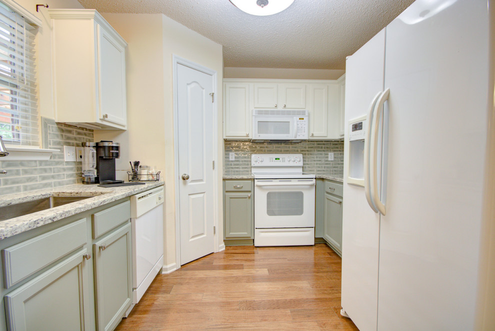 Inspiration for a mid-sized transitional u-shaped medium tone wood floor and brown floor eat-in kitchen remodel with an undermount sink, shaker cabinets, green cabinets, granite countertops, green backsplash, ceramic backsplash, white appliances, no island and multicolored countertops