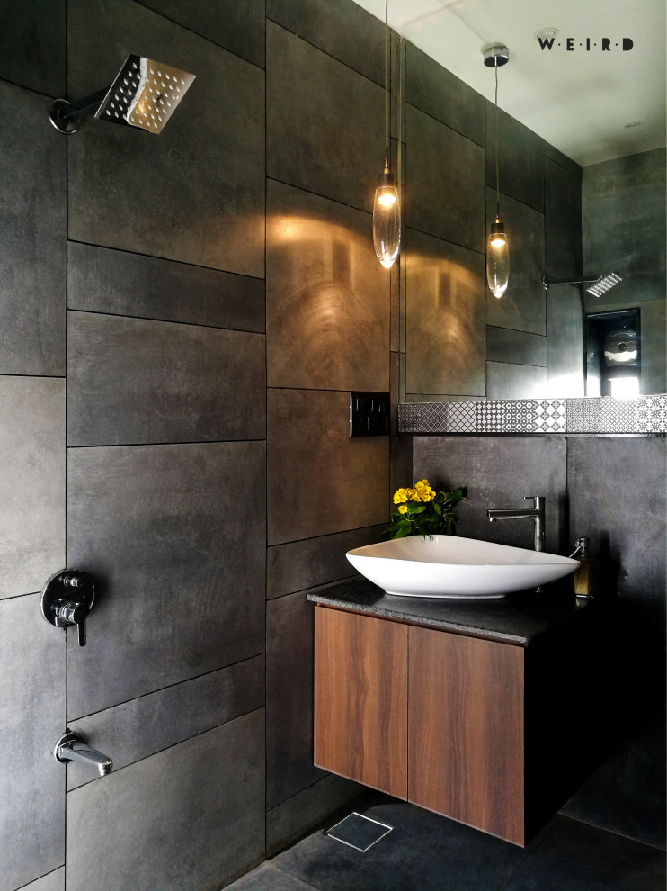 This is an example of a contemporary bathroom in Ahmedabad with flat-panel cabinets, dark wood cabinets, grey tiles, a vessel sink, grey floors, black worktops, a single sink and a floating vanity unit.