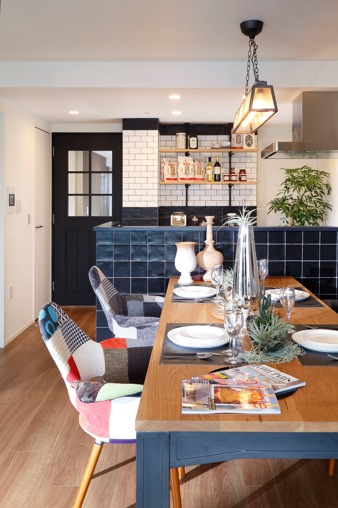 This is an example of an eclectic dining room in Tokyo with white walls and medium hardwood floors.