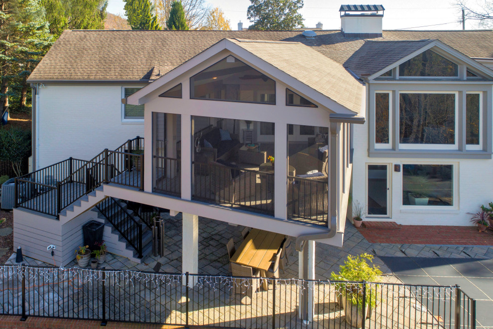 Cette photo montre un grand porche d'entrée de maison arrière chic avec une moustiquaire, une extension de toiture et un garde-corps en métal.