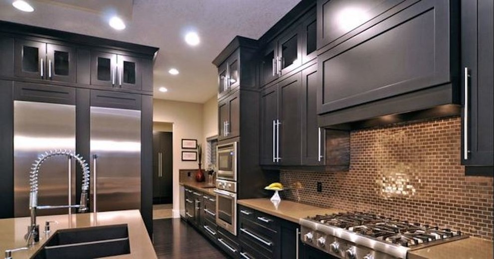 Inspiration for a large galley light wood floor enclosed kitchen remodel in Cedar Rapids with a drop-in sink, beaded inset cabinets, black cabinets, multicolored backsplash, stainless steel appliances and an island