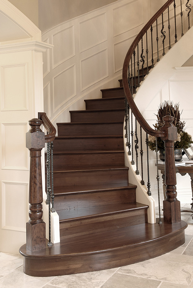 Imagen de escalera curva clásica grande con escalones de madera, contrahuellas de madera y barandilla de madera