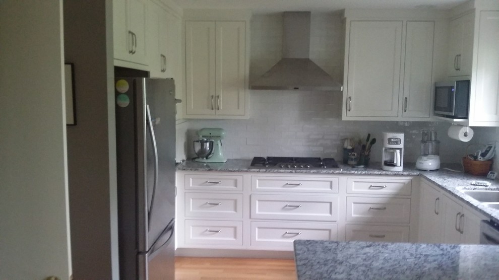 Open concept kitchen - mid-sized transitional u-shaped medium tone wood floor and brown floor open concept kitchen idea with a double-bowl sink, shaker cabinets, white cabinets, granite countertops, gray backsplash, subway tile backsplash, stainless steel appliances and an island