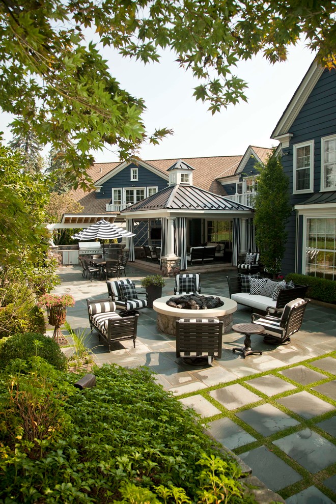 This is an example of a large traditional backyard patio in Detroit with an outdoor kitchen and a roof extension.