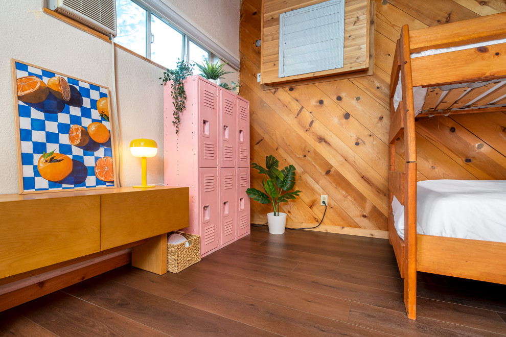 Cette image montre une chambre mansardée ou avec mezzanine bohème de taille moyenne avec un mur marron, un sol en vinyl, un poêle à bois, un manteau de cheminée en brique, un sol marron et poutres apparentes.