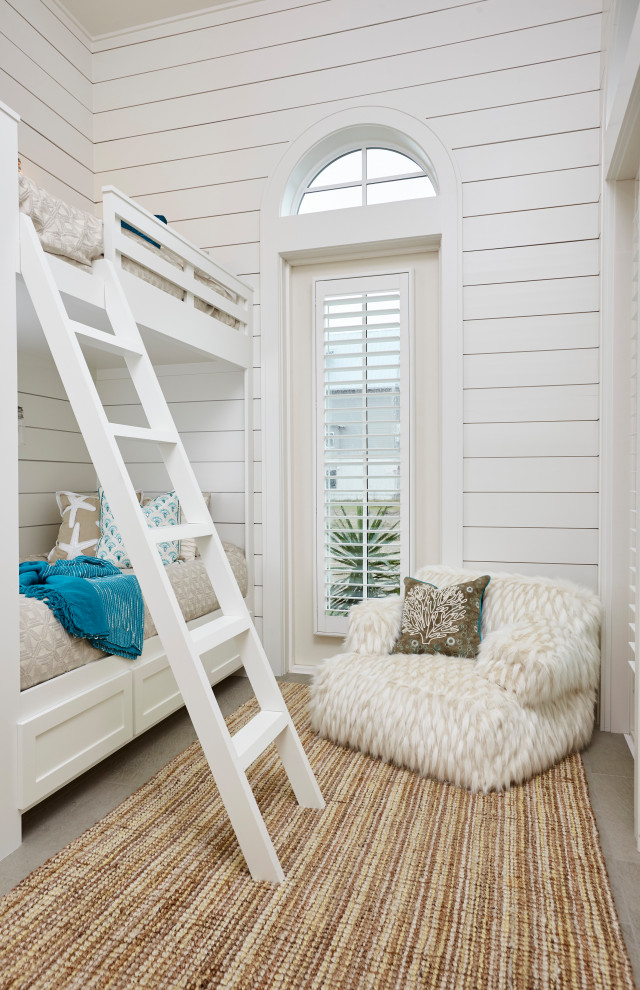 This is an example of a beach style gender-neutral kids' bedroom for kids 4-10 years old in Austin with white walls, grey floor and planked wall panelling.