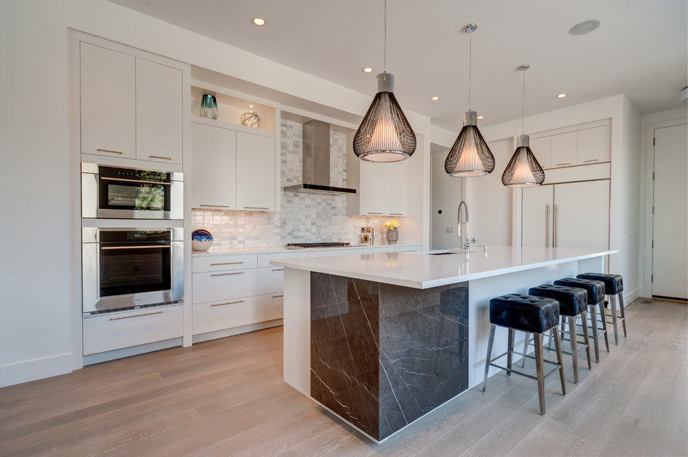 Design ideas for a contemporary l-shaped kitchen in New Orleans with an undermount sink, flat-panel cabinets, white cabinets, grey splashback, panelled appliances, medium hardwood floors, with island and grey floor.