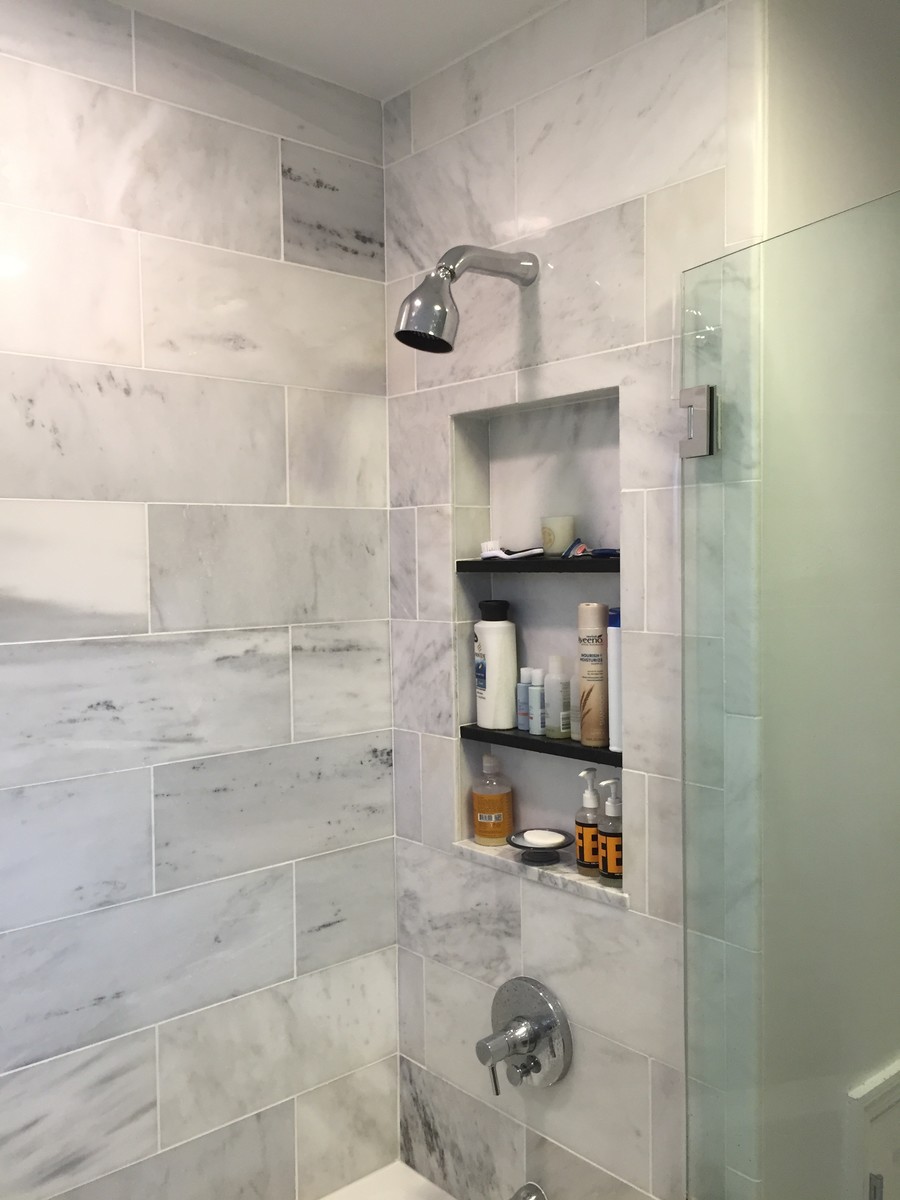 Photo of a small contemporary bathroom in New York with shaker cabinets, black cabinets, a drop-in tub, a shower/bathtub combo, a one-piece toilet, gray tile, marble, grey walls, ceramic floors, an integrated sink, quartzite benchtops, multi-coloured floor and a hinged shower door.