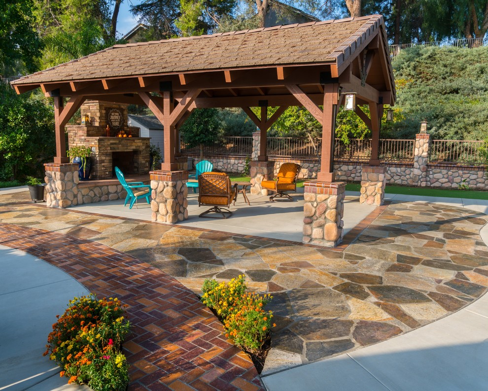 This is an example of a large country backyard patio in Los Angeles with natural stone pavers and a gazebo/cabana.