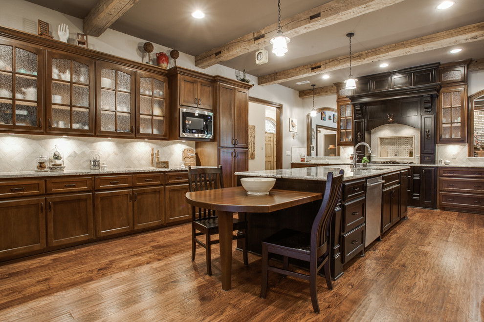 Large country u-shaped eat-in kitchen in Dallas with glass-front cabinets, medium wood cabinets, granite benchtops, stone tile splashback, stainless steel appliances, medium hardwood floors, with island and brown floor.