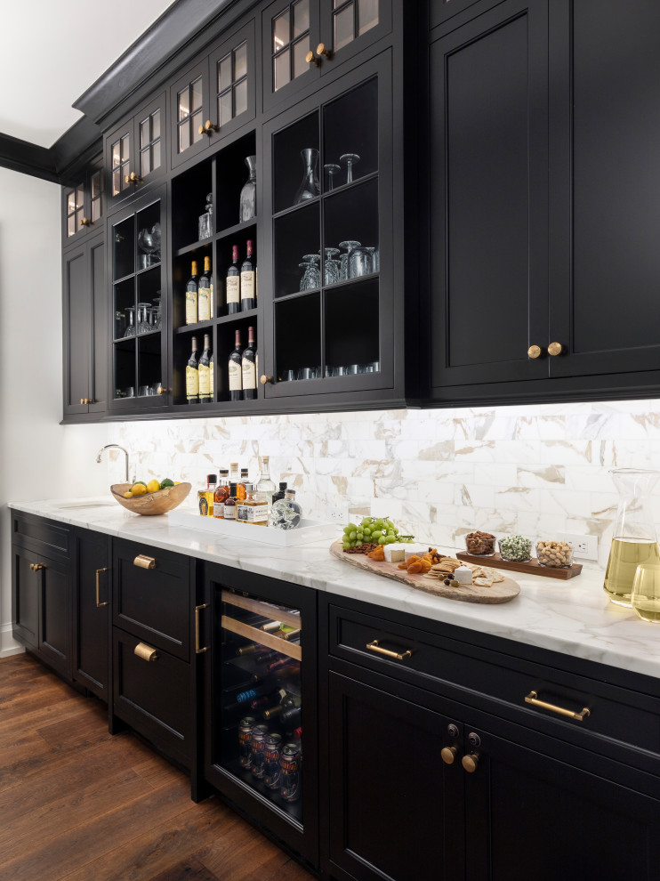 This is an example of a large country single-wall wet bar in Detroit with an undermount sink, shaker cabinets, black cabinets, multi-coloured splashback, medium hardwood floors, brown floor and white benchtop.