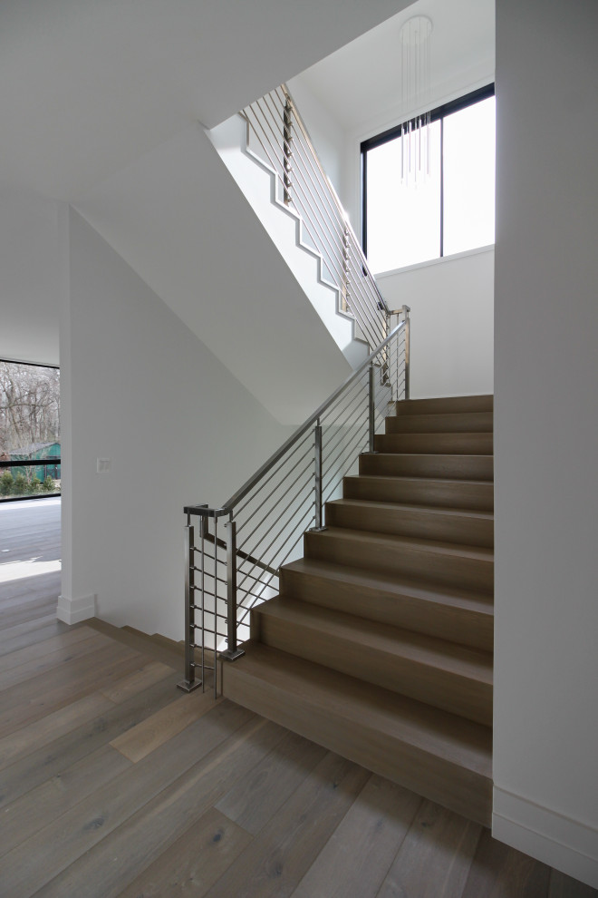 Стильный дизайн: деревянная лестница на больцах, среднего размера в стиле модернизм с деревянными ступенями, металлическими перилами и стенами из вагонки - последний тренд