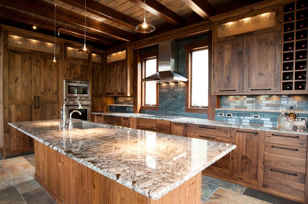 This is an example of a large country l-shaped open plan kitchen in Denver with an undermount sink, shaker cabinets, medium wood cabinets, granite benchtops, blue splashback, glass tile splashback, stainless steel appliances, slate floors, with island, multi-coloured floor and multi-coloured benchtop.