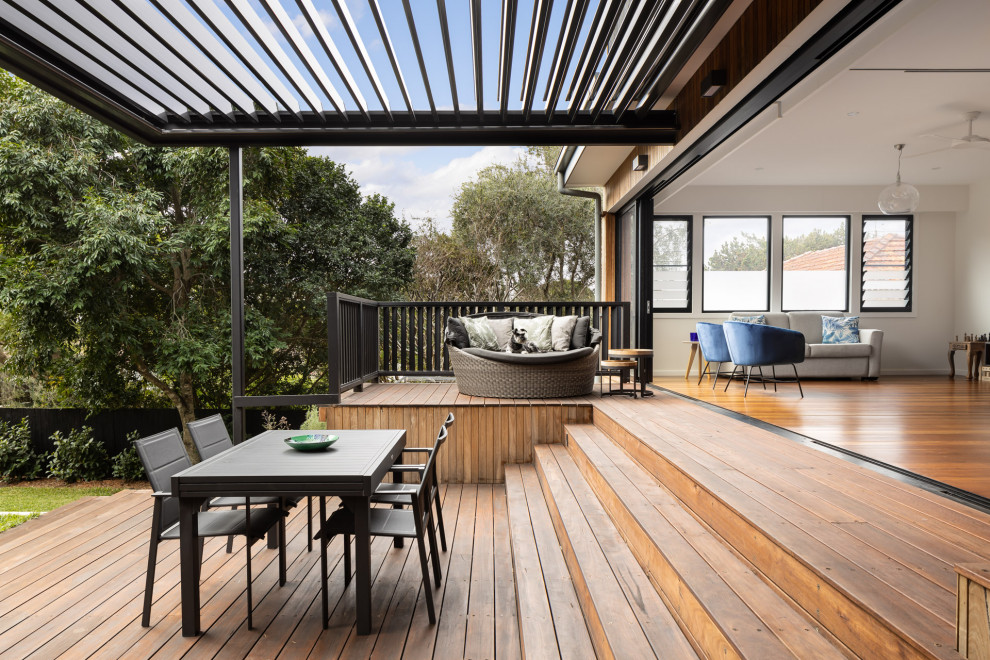 This is an example of a mid-sized contemporary backyard and ground level deck in Sydney with a pergola.