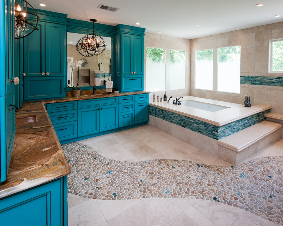 Photo of a large mediterranean master bathroom in DC Metro with blue cabinets, recessed-panel cabinets, a drop-in tub, beige tile, ceramic tile, beige walls, pebble tile floors and granite benchtops.