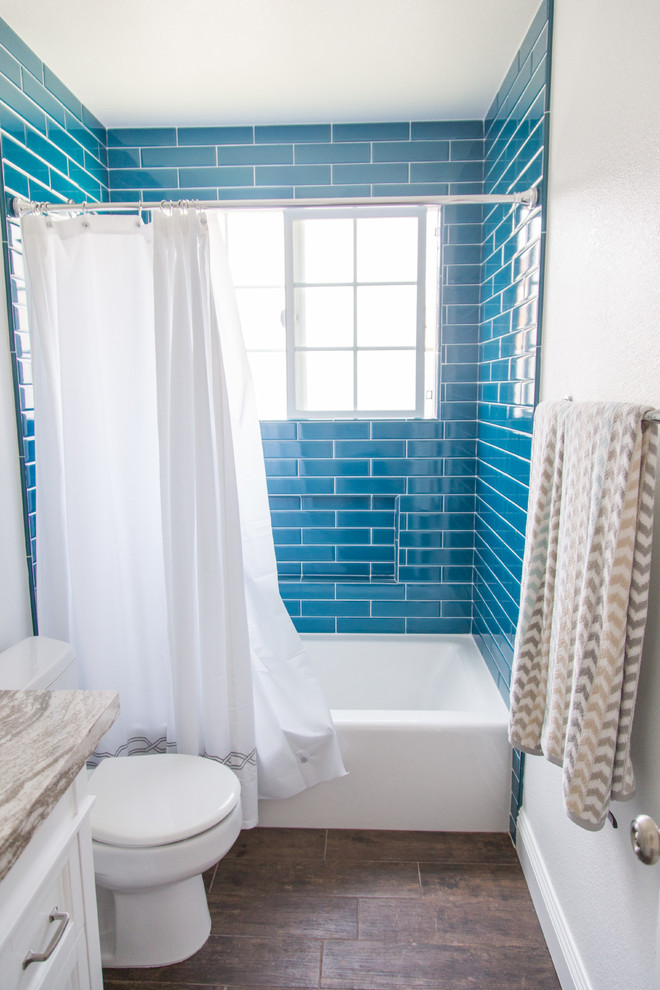 Mid-sized transitional 3/4 bathroom in Orange County with an alcove tub, a shower/bathtub combo, a two-piece toilet, blue tile, subway tile, white walls, dark hardwood floors, an undermount sink, brown floor, a shower curtain, shaker cabinets, white cabinets and quartzite benchtops.