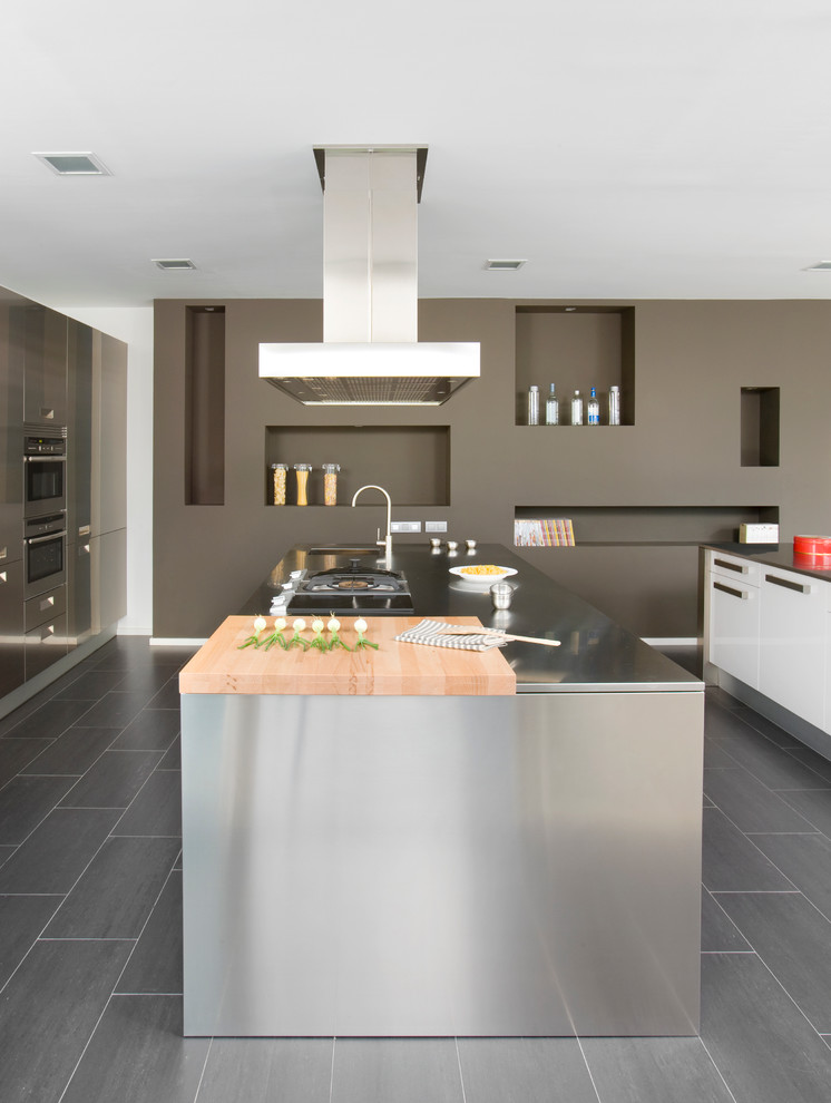 Large contemporary u-shaped kitchen in Other with an undermount sink, stainless steel benchtops, stainless steel appliances, ceramic floors, with island, flat-panel cabinets, white cabinets and brown splashback.