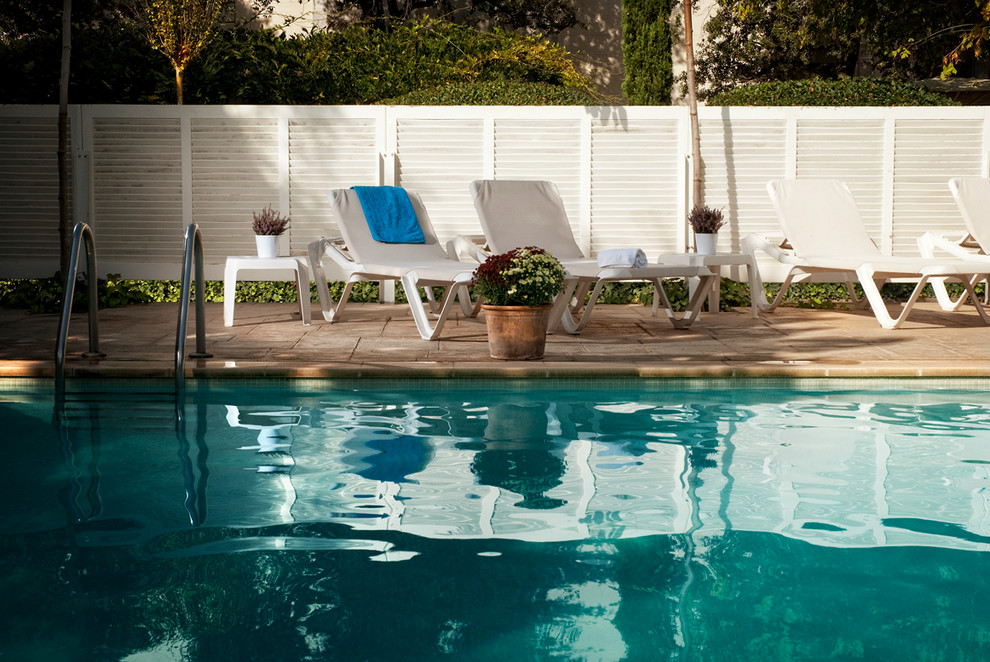Modelo de casa de la piscina y piscina alargada clásica renovada de tamaño medio rectangular en patio con suelo de baldosas