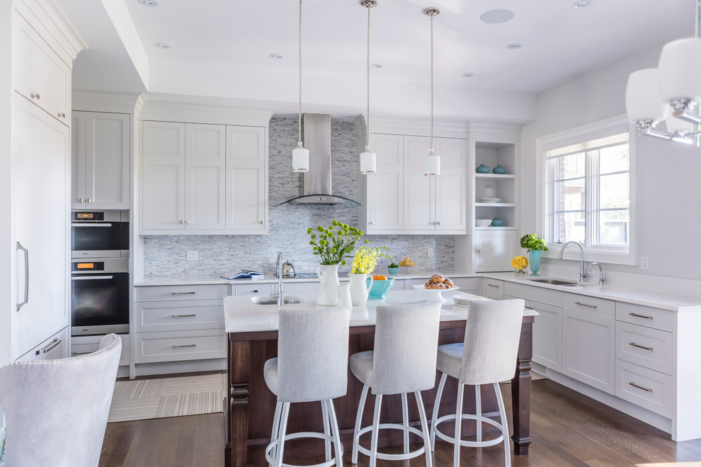 Transitional u-shaped medium tone wood floor eat-in kitchen photo in Toronto with an undermount sink, recessed-panel cabinets, white cabinets, quartz countertops, white backsplash, stone tile backsplash, stainless steel appliances and an island
