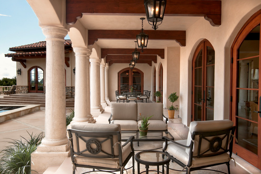 Inspiration for a large mediterranean backyard verandah in San Diego with natural stone pavers and a roof extension.