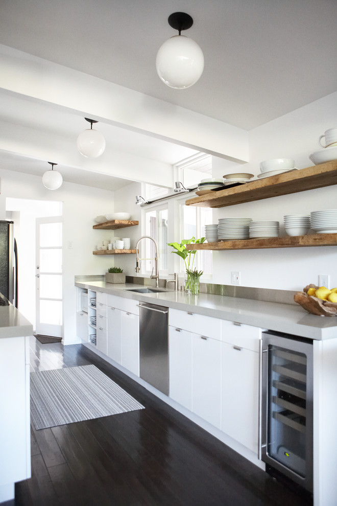Contemporary galley kitchen in San Francisco with an undermount sink, flat-panel cabinets, white cabinets, stainless steel appliances, dark hardwood floors, black floor, grey benchtop and with island.