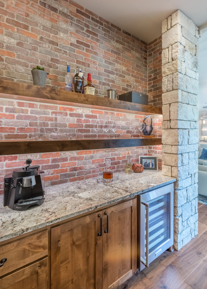 Photo of a mid-sized country single-wall home bar in Austin with no sink, flat-panel cabinets, medium wood cabinets, granite benchtops, red splashback, brick splashback, medium hardwood floors, brown floor and grey benchtop.