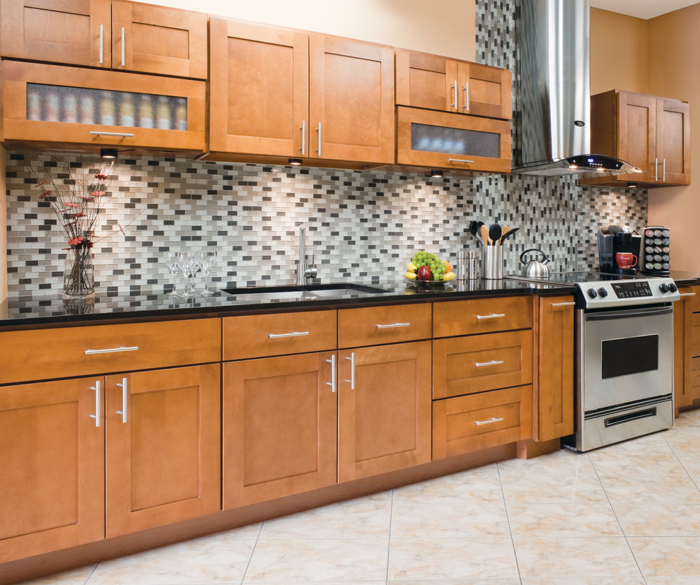 Photo of a mid-sized contemporary single-wall separate kitchen in Philadelphia with an undermount sink, beaded inset cabinets, medium wood cabinets, granite benchtops, grey splashback, glass tile splashback, stainless steel appliances, ceramic floors and no island.