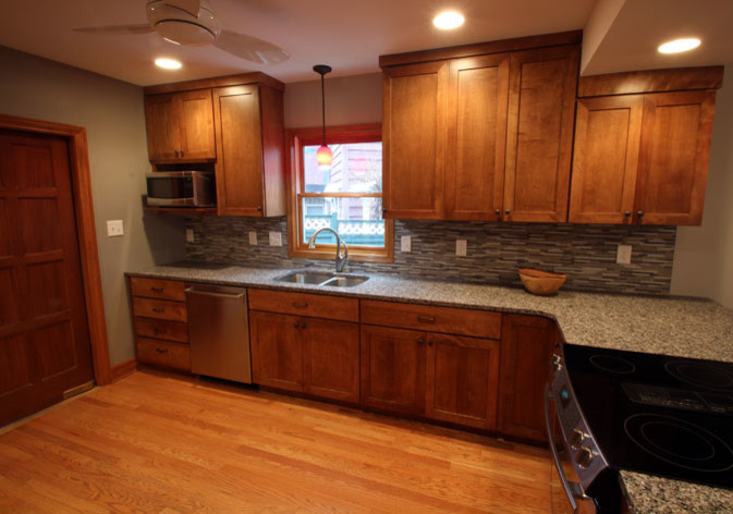 Mid-sized transitional l-shaped light wood floor eat-in kitchen photo with an undermount sink, shaker cabinets, dark wood cabinets, granite countertops, multicolored backsplash, mosaic tile backsplash, stainless steel appliances and a peninsula