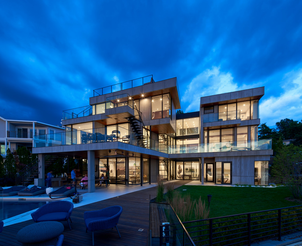 На фото: большой, трехэтажный частный загородный дом в стиле модернизм с облицовкой из бетона, плоской крышей и зеленой крышей