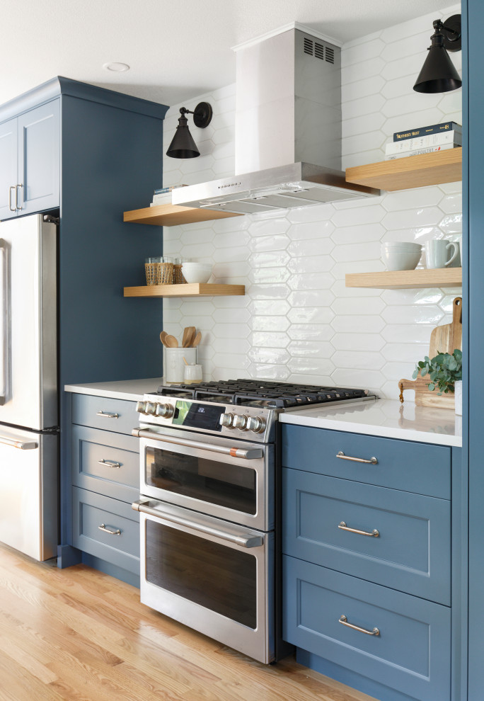 Inspiration for a mid-sized transitional galley eat-in kitchen in Portland with an undermount sink, recessed-panel cabinets, blue cabinets, quartz benchtops, white splashback, cement tile splashback, stainless steel appliances, light hardwood floors, no island and white benchtop.